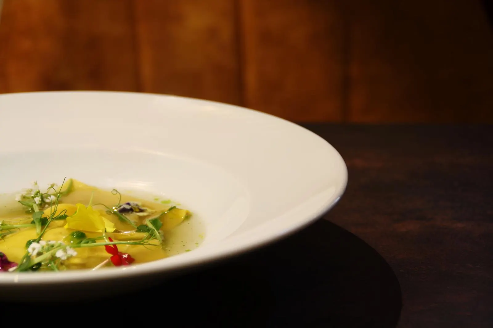 Raviole dans un bouillon clair aux herbes et fleurs comestibles