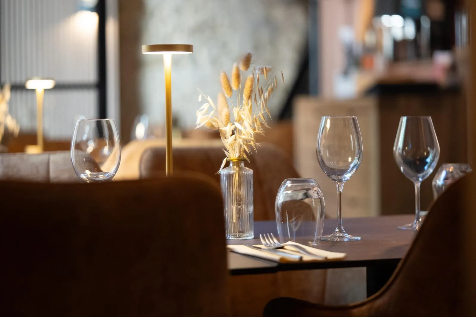Tables dressées avec verres à vin et lampe dorée aux Magnolias